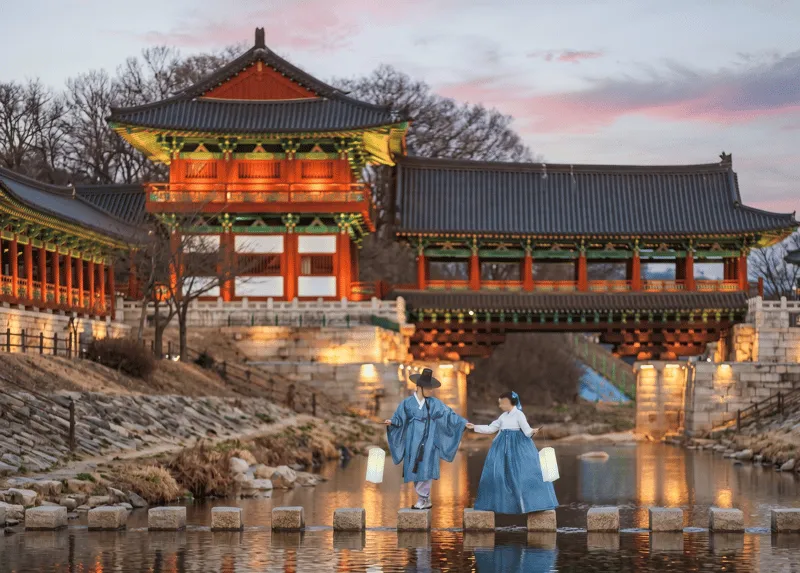 Visitors in traditional hanbok walking the lantern-lit Woljeonggyo Bridge on a private gyeongju city tour in Gyeongju, South Korea
